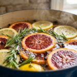 Steaming citrus and rosemary stovetop simmer pot with sliced blood oranges and fresh herbs bubbling gently