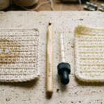 Side-by-side comparison of unmercerized cotton crochet swatch absorbing water versus acrylic swatch with beading water on travertine