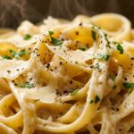 Ultra close-up macro of glossy ribbons of fettuccine pasta coated in velvety garlic parmesan cream sauce