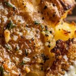 Ultra close-up macro of crispy golden smashed baby Yukon potato dipping into velvety lemon whipped feta dip