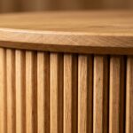 Ultra close-up macro craftsmanship shot of handmade fluted round oak coffee table with half-round wooden flutes