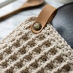 Macro texture of thick oatmeal cotton thermal stitch crochet potholder with leather hanging loop