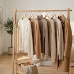 Curated autumn clothing rack in soft morning daylight with neutral wool knitwear and coats