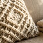 Modern textured cream and oatmeal crochet throw pillow with alpine waffle stitch on beige linen sofa