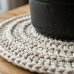 Ultra close-up macro of thick circular crochet hot pad trivet under cast iron Dutch oven