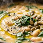Ultra close-up macro of steaming creamy white bean and spinach soup with extra virgin olive oil and toasted pumpkin seeds