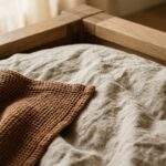 Ultra close-up macro texture of washed Belgian linen duvet in oatmeal and waffle throw on oak platform bed