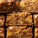 Ultra close-up macro food photography of freshly sliced chewy brown butter apple blondies stacked with caramelized cinnamon apples and flaky sea salt