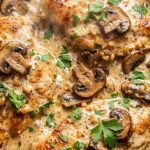 Ultra close-up macro texture of golden seared chicken cutlet smothered in bubbling garlic herb cream sauce with caramelized cremini mushrooms