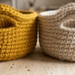 Macro close-up of handcrafted chunky round crochet basket with integrated cutout handle in mustard gold and natural oatmeal yarn