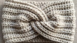 Ultra close-up macro texture of handmade crochet twisted ear warmer headband with ribbed stitch texture in oatmeal wool blend yarn