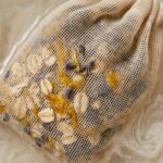 Ultra close-up macro of unbleached muslin bath tea bag steeping in warm water with milky oat extract and dried lavender