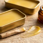 Ultra close-up macro of smooth golden homemade beeswax lip balm in aluminum slider tins