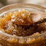 Ultra close-up macro of homemade golden honey brown sugar lip scrub in mini glass apothecary jar