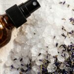 Ultra close-up macro texture of DIY magnesium spray in amber glass bottle with white magnesium flakes and dried lavender buds
