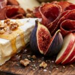 Extreme close-up macro of an autumn charcuterie board with brie, raw honeycomb, fresh figs, and cured beef ribbons