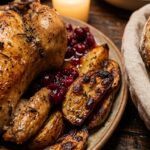 Ultra close-up macro of an abundant Friendsgiving dining feast centerpiece with golden roast chicken, potatoes, and warm bread