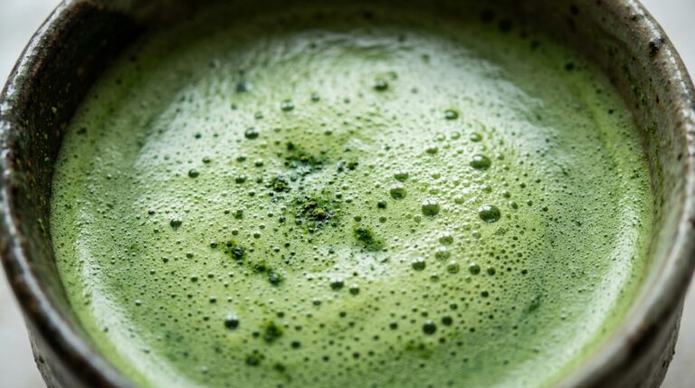 Ultra close-up macro texture of freshly whisked vibrant emerald green matcha tea with micro-foam bubbles in ceramic bowl