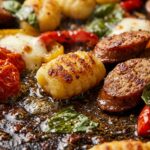 Ultra close-up macro food photography of crispy golden roasted sheet pan gnocchi and browned halal sausage with burst cherry tomatoes and melted mozzarella