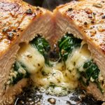 Ultra close-up macro texture of golden seared spinach stuffed chicken breast sliced open with molten mozzarella and garlic spinach filling