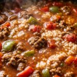 Ultra close-up macro texture of rich stuffed pepper soup with ground beef, vibrant bell peppers, and rice simmering in tomato broth