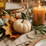 Extreme close-up macro of a Thanksgiving centerpiece with silver dollar eucalyptus, miniature white pumpkins, and warm glowing candles