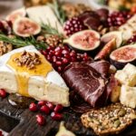 Extreme macro close-up of a lavish Thanksgiving charcuterie board with brie cheese, honey drizzle, halal beef bresaola, pomegranate seeds, and figs