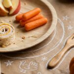 Extreme macro close-up of a Thanksgiving kids table setting with brown butcher paper, bamboo plate, kid-friendly feast nibbles, and colorful crayons